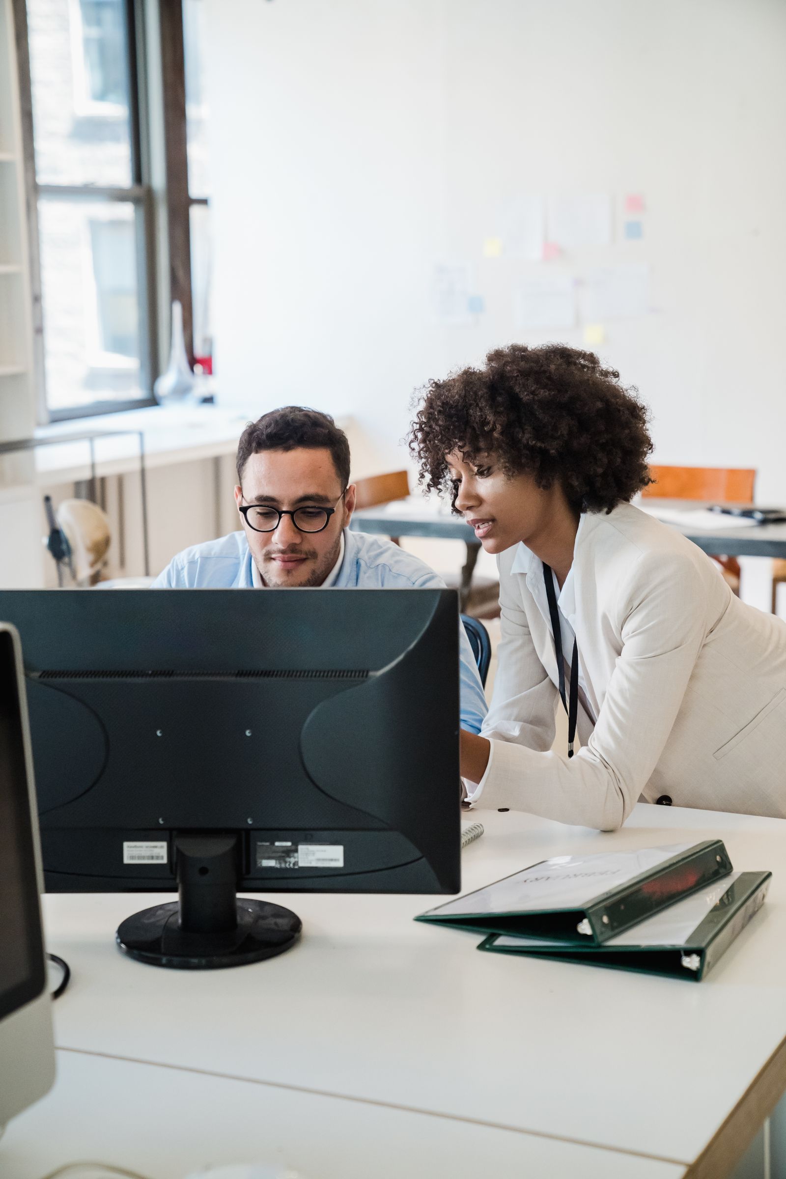 Two office colleagues discussing in front of a computer screen