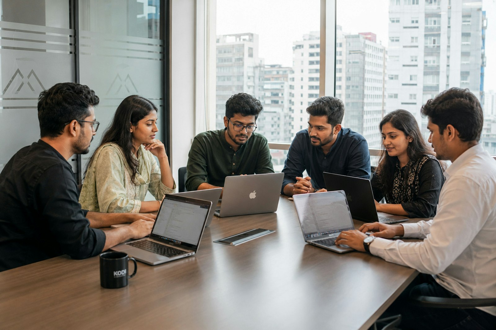 Colleagues collaborating around a conference table with laptops
