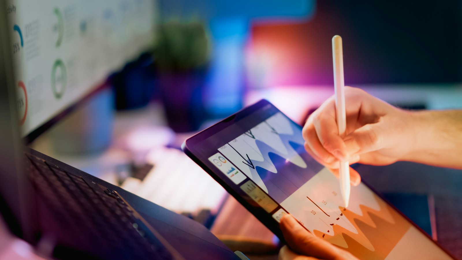 Person using a stylus on a tablet displaying charts and interface elements