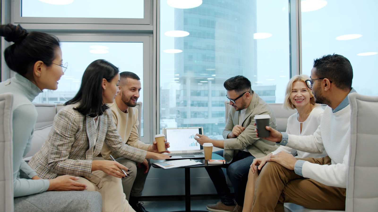 Diverse group of colleagues gathered around a laptop in a modern office meeting