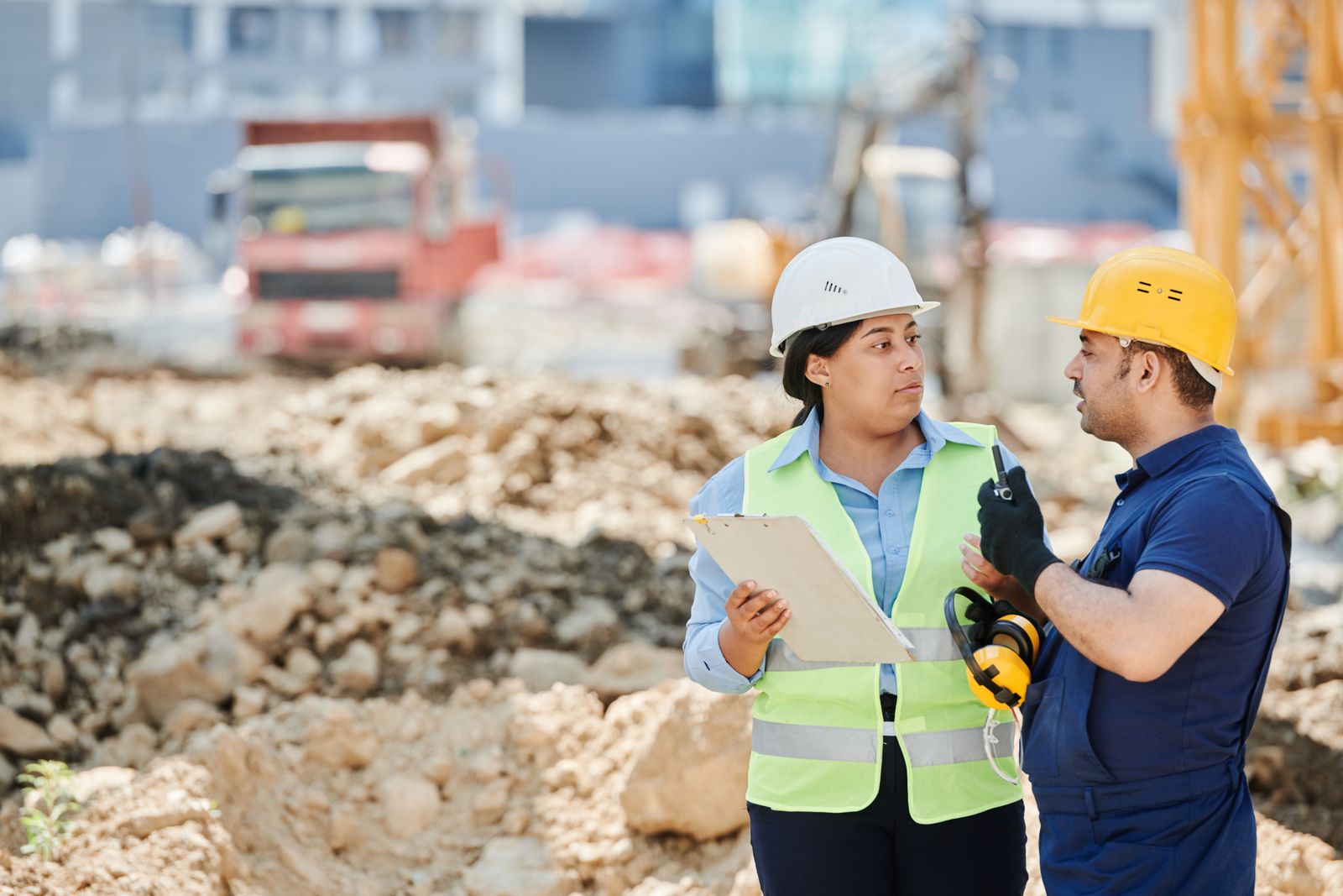 Site supervisor and colleague in hard hats reviewing progress on site