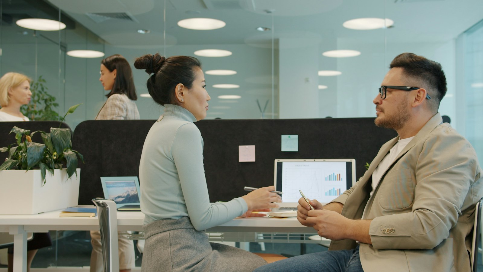Two coworkers discussing a process at a desk in an office