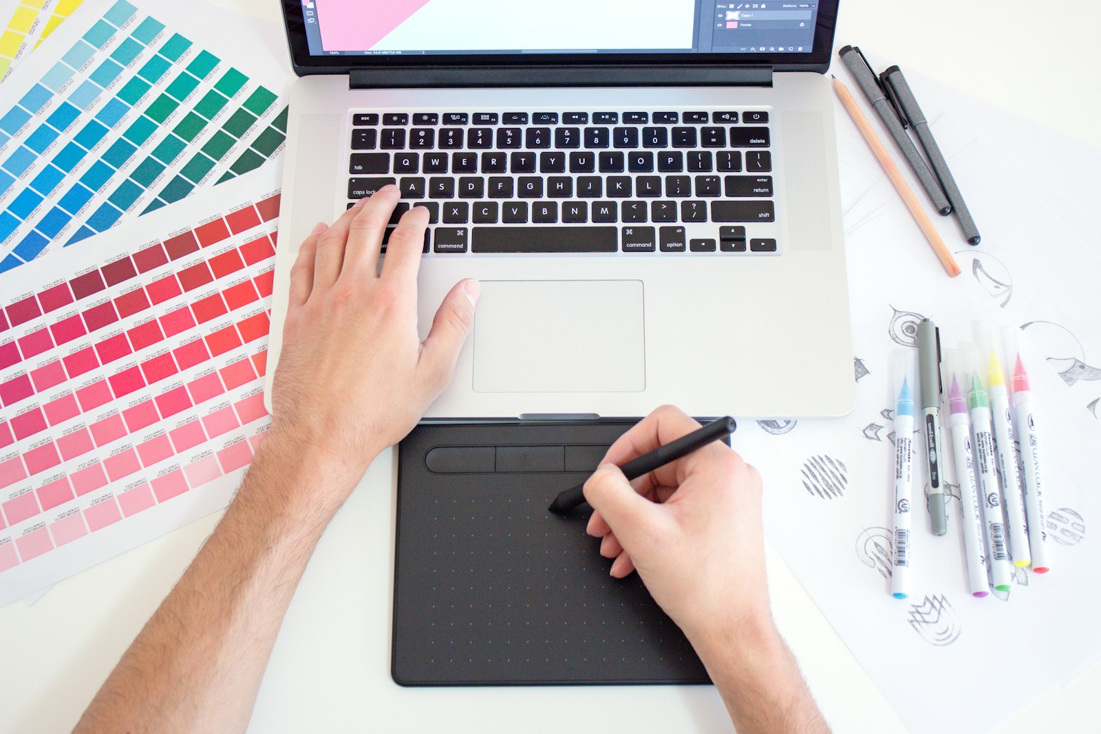Designer working on brand visuals with a laptop and color swatches