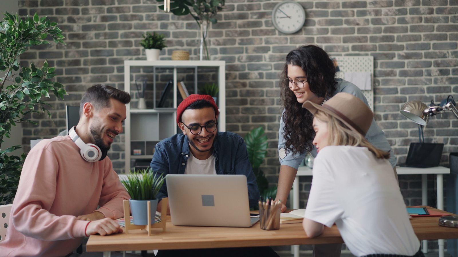 A remote team sitting around a table working on laptops