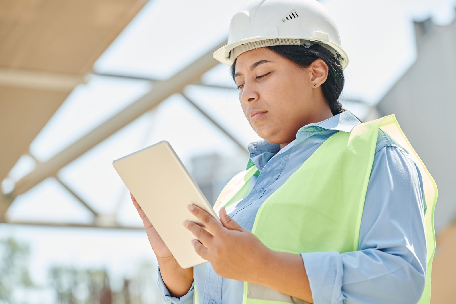 Engineer in a hard hat reviewing project details on a tablet
